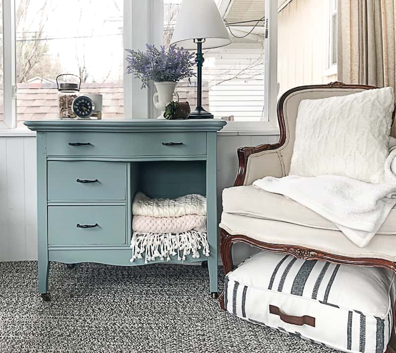 A blue dresser sits next to a white armchair.