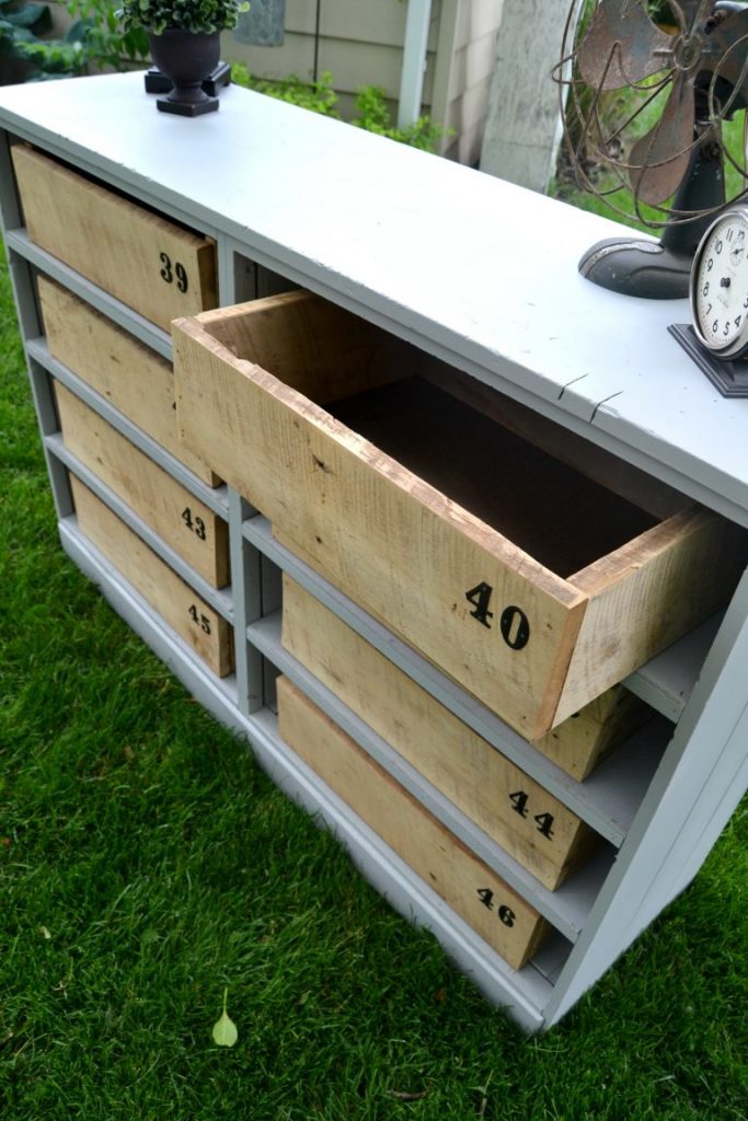 A blue shelf unit with wooden boxes in it.