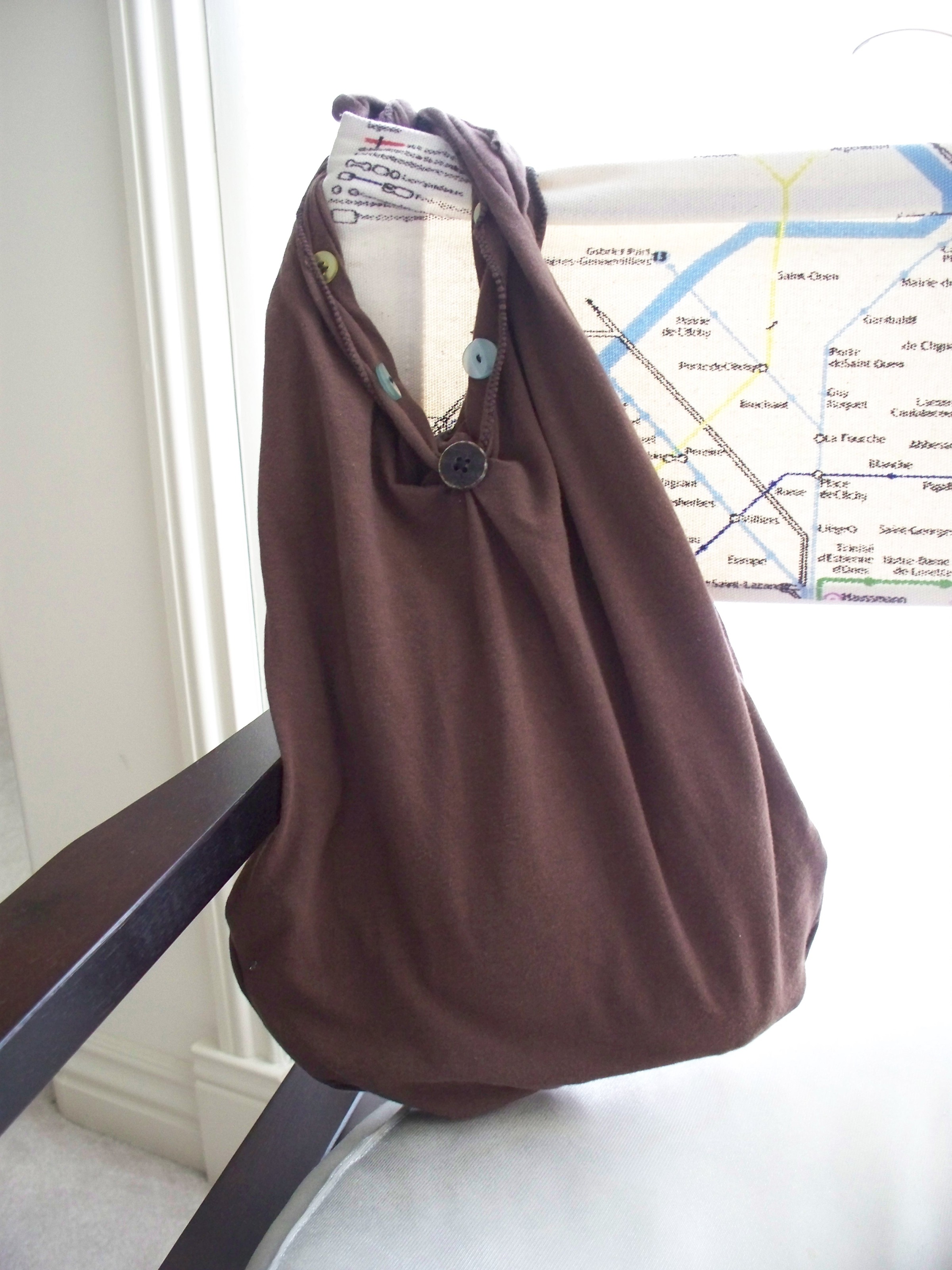 A brown handbag with buttons hangs from a chair arm.