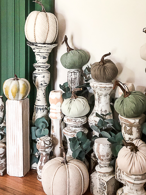 White, distressed table legs serve as pedestals for fabric pumpkins. 