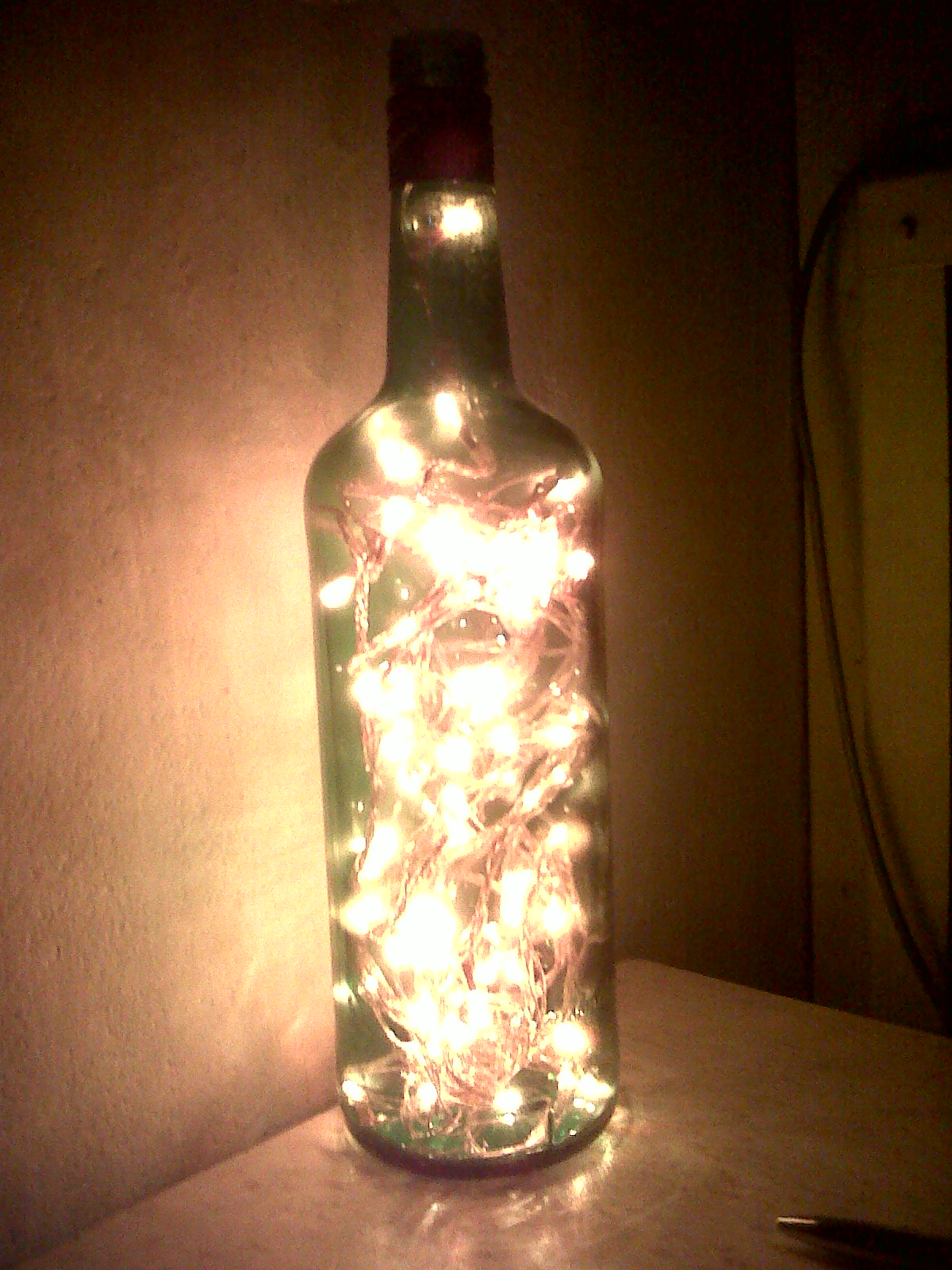 Empty wine bottle is filled with a string of lit LED lights.