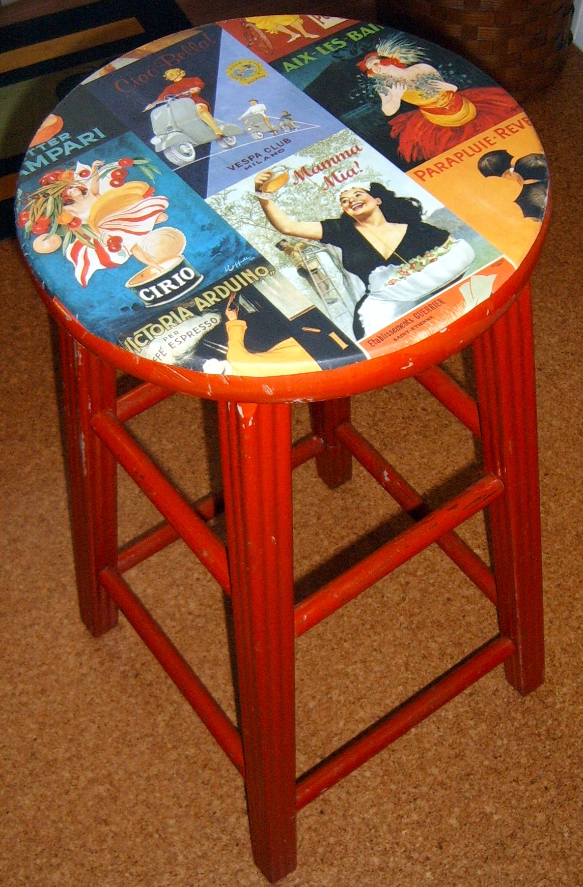 Red stool with decoupaged images on the seat. 