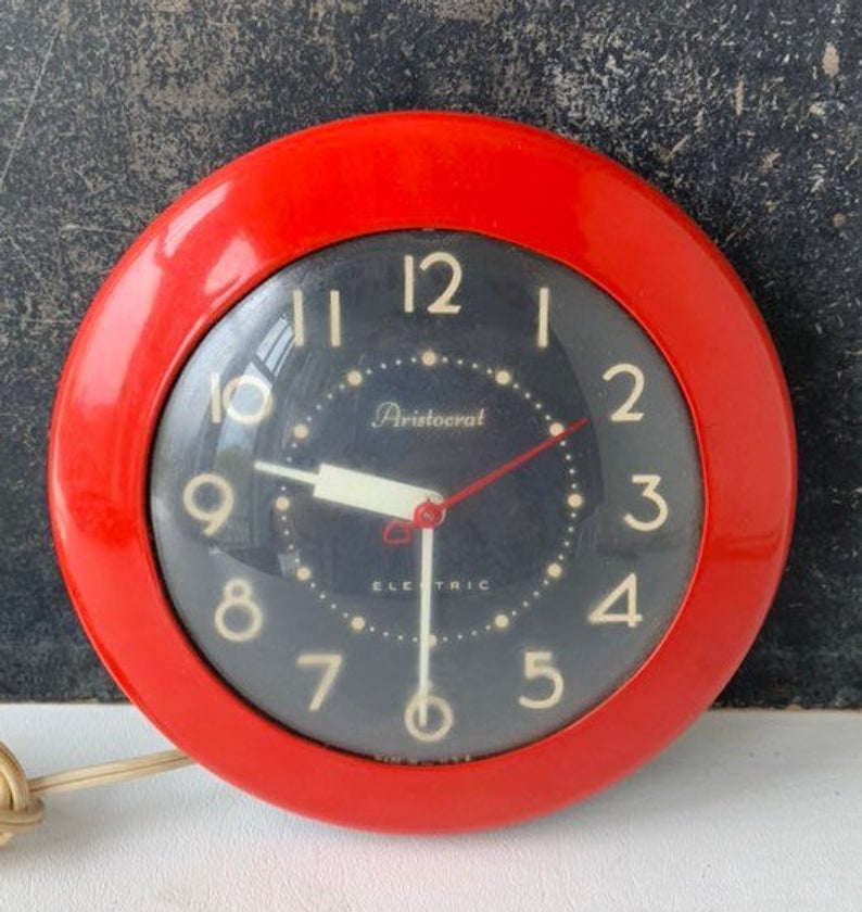 Red metal wall clock with black back and white numbers.