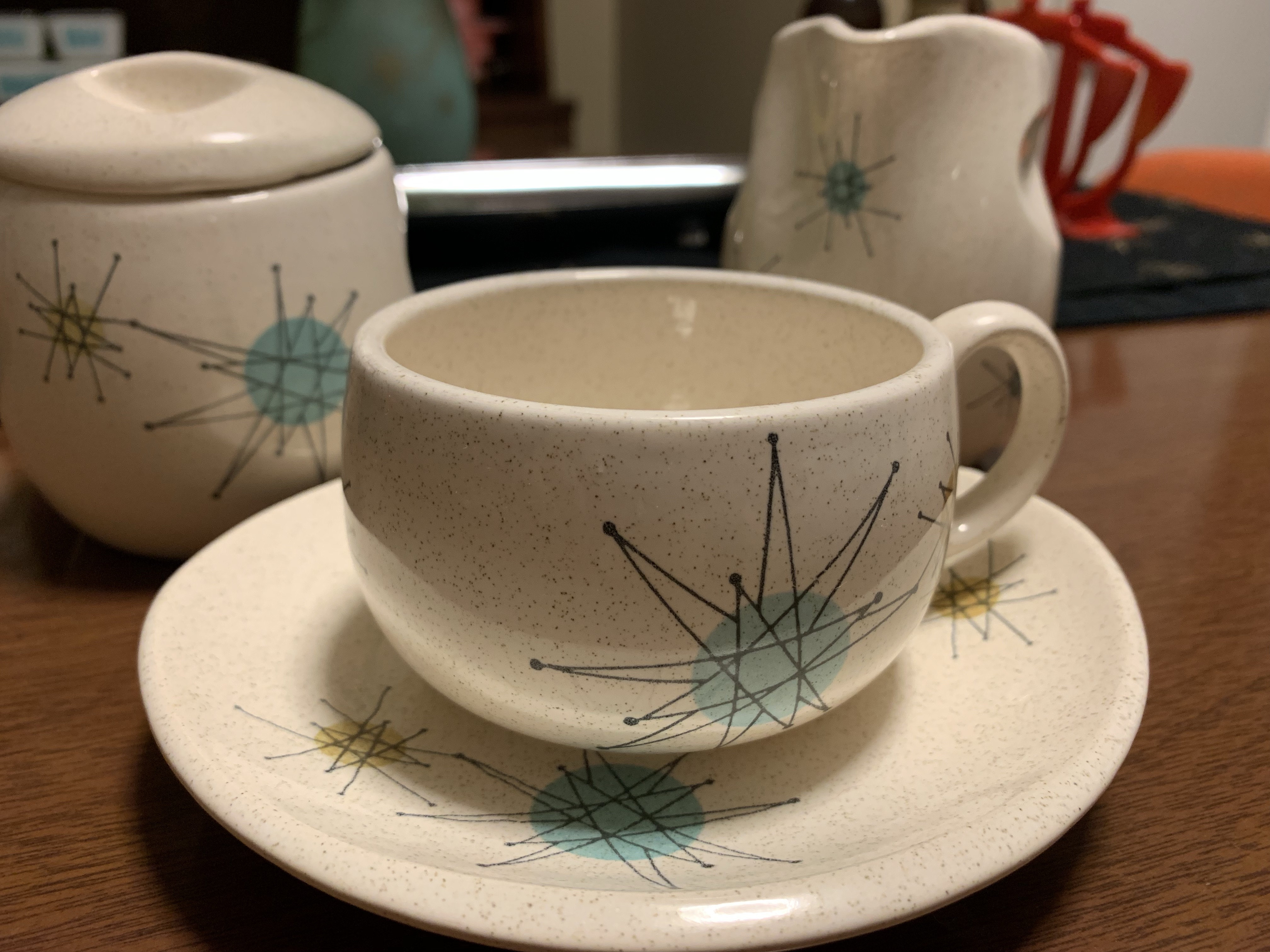 White cup and sauce with blue and black starburst pattern.