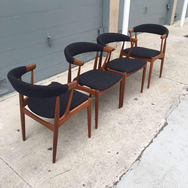 Four wooden chairs upholstered with dark fabric.