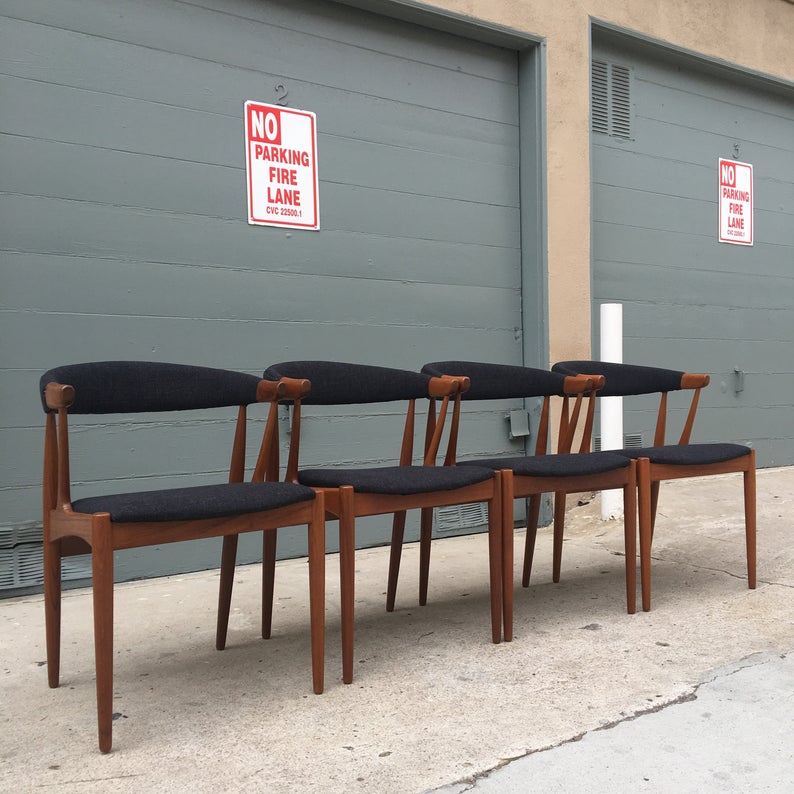 Four wooden chairs upholstered with dark fabric.