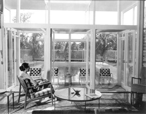 Black and white image of woman in glass sitting room.