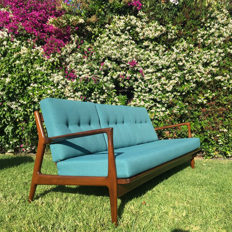 Wooden sofa with teal upholstery in a garden.